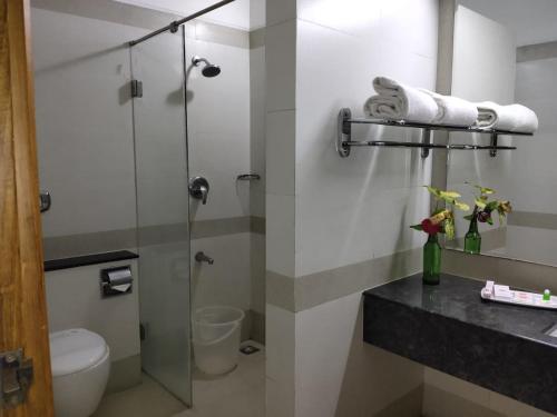 a bathroom with a glass shower and a toilet at Hotel Western Gatz in Theni