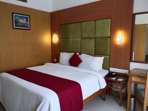 een hotelkamer met een groot bed met een rode deken bij Hotel Western Gatz in Theni
