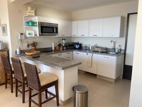 a kitchen with white cabinets and a counter with chairs at Bonito departamento pie de playa en el mejor condominio de manzanillo, Ponto Horizonte. Hermosa vista, hasta para 8 personas. Ambiente familiar. in Manzanillo