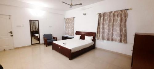 um quarto com uma cama, uma cadeira e um espelho em Krida Inn em Chennai
