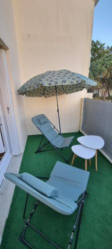 - une terrasse avec une table, 2 chaises et un parasol dans l'établissement DUPLEX PISCINE MER, à La Rochelle