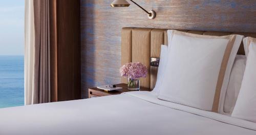 a bed with white pillows and a vase of flowers at Jumeirah Beach Hotel Dubai in Dubai