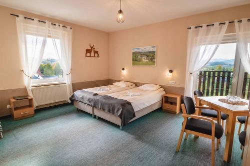 a bedroom with a bed and a table and two windows at Granada Pensjonat & SPA in Duszniki Zdrój