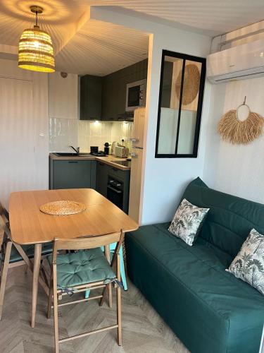 un salon avec un canapé vert et une table dans l'établissement Tropical Duplex : Bord de mer + Piscine, à Frontignan