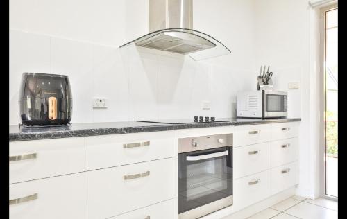 a white kitchen with a microwave and a stove at Mildura Holiday Villas in Mildura