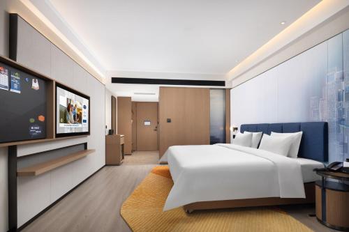 a bedroom with a large white bed and a flat screen tv at Hampton by Hilton Shenzhen Futian Huaqiangbei in Shenzhen