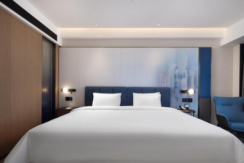 a bedroom with a large white bed and a blue chair at Hampton by Hilton Shenzhen Futian Huaqiangbei in Shenzhen