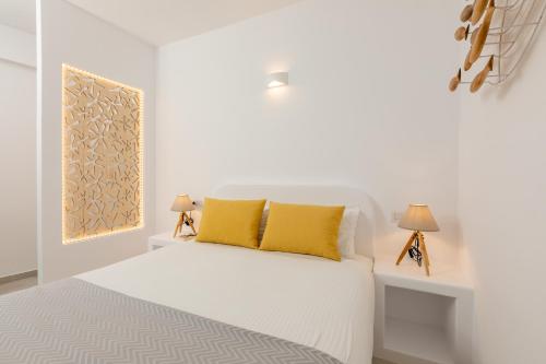 a white bedroom with a bed with yellow pillows at Nikolas Hotel in Karterados