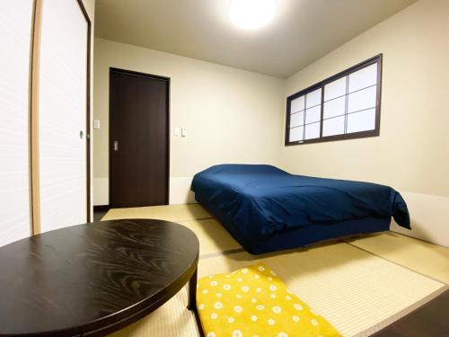 京都的住宿－KAMON INN AIHUKA，一间卧室配有一张蓝色的床和一张桌子