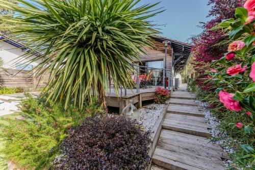 un chemin en bois menant à une maison fleurie dans l'établissement Villa AMAYA, Pyla/ Le Moulleau, à La Teste-de-Buch
