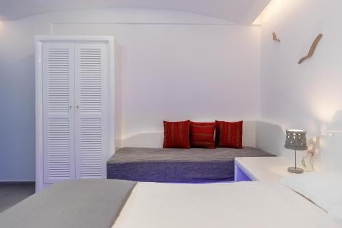 a white bedroom with two beds with red pillows at Nikolas Hotel in Karterados