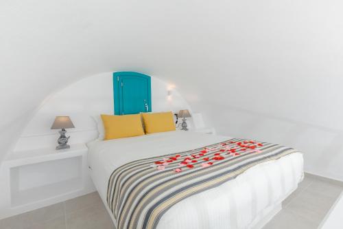 a bedroom with a white bed with red flowers on it at Nikolas Hotel in Karterados