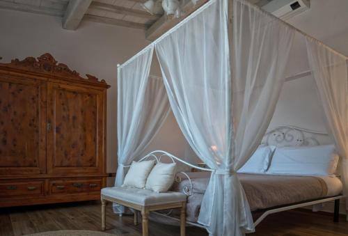 ein Schlafzimmer mit einem Himmelbett und einem Stuhl in der Unterkunft Casa Cantagalli in Tavarnuzze