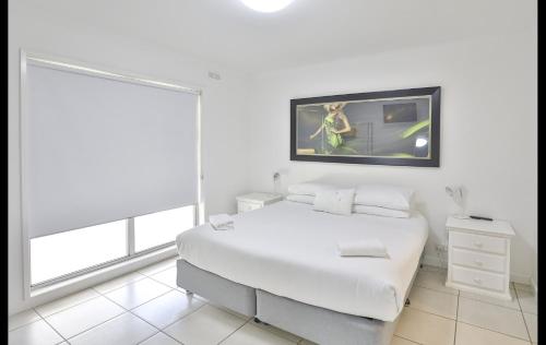 a white bedroom with a large white bed and a window at Mildura Holiday Villas in Mildura