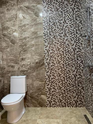 y baño con aseo y ducha de azulejos. en Orange Villa Kvariati en Kvariati