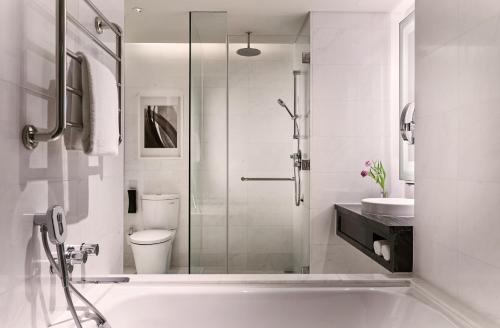 a white bathroom with a tub and a toilet at Carlton City Hotel Singapore in Singapore