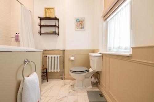 uma casa de banho com um WC, um lavatório e uma janela em Traditional Treasure – 3 Bedroom Home by Hyde Park em Londres