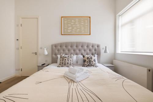 een witte slaapkamer met een groot bed en een groot raam bij Luxury and Cool 2 bedroom in Notting Hill in Londen