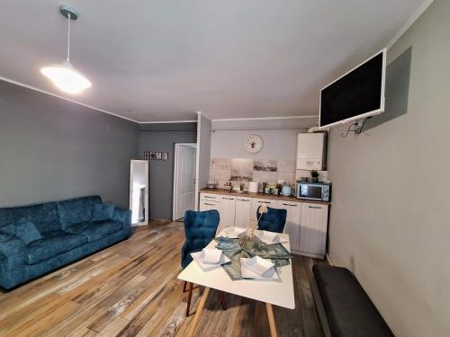 Una sala de estar con una mesa y un sofá azul. en Magic Apartments Hunedoara, en Hunedoara