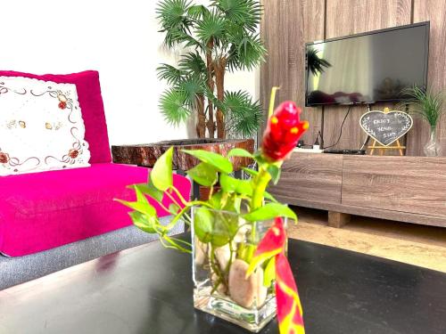 a vase with flowers on a table in a living room at Nature's Cottage By Adagaya Villa Langkawi in Pantai Cenang