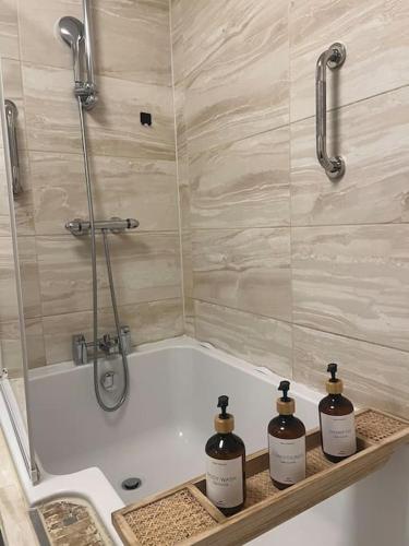 a bathroom with a bath tub with three bottles of soap at Birminghams Finest in Birmingham