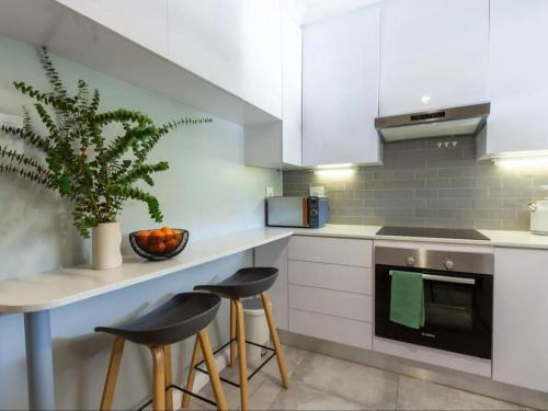a kitchen with white cabinets and a counter with stools at Parioli Court in Cape Town