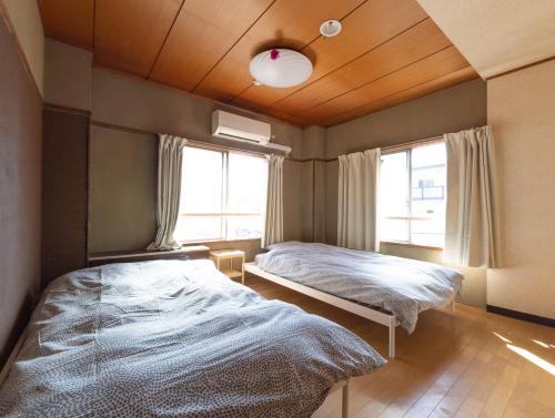 a bedroom with two beds and a window at Hostel JAQ takamatsu in Takamatsu