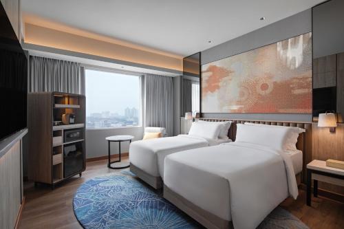 a bedroom with a white bed and a large window at Mövenpick Hotel Jakarta City Centre in Jakarta