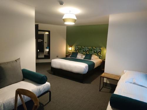 a hotel room with two beds and a couch at Clos De La Vaupalière - Rouen in La Vaupalière