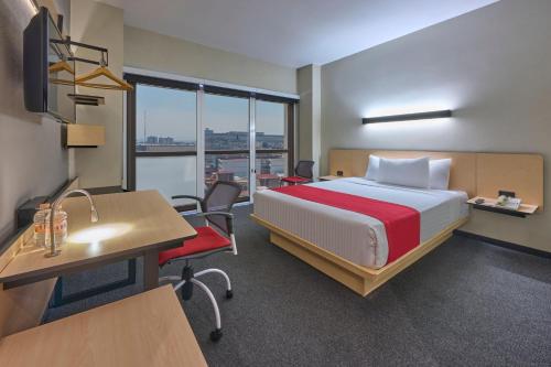 a hotel room with a bed and a desk and a desk at City Express Plus by Marriott Patio Universidad in Mexico City