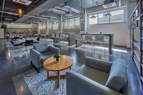 a lobby with couches and tables and a bar at City Express Plus by Marriott Ciudad de México Patio Universidad in Mexico City