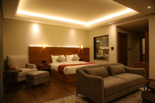 a hotel room with a bed and a couch and chairs at Casa Galwan in Leh