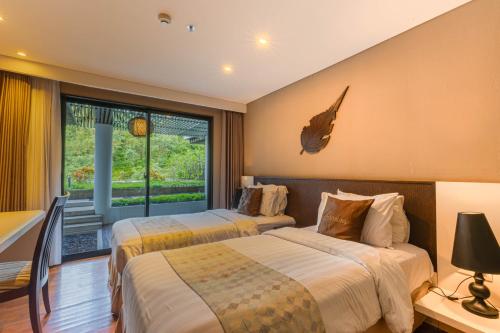 two beds in a hotel room with a window at The Sterling Villas in Uluwatu
