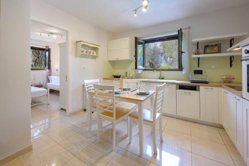 a kitchen with white cabinets and a table and chairs at VILLA BOUGARINI in Ieromónachos