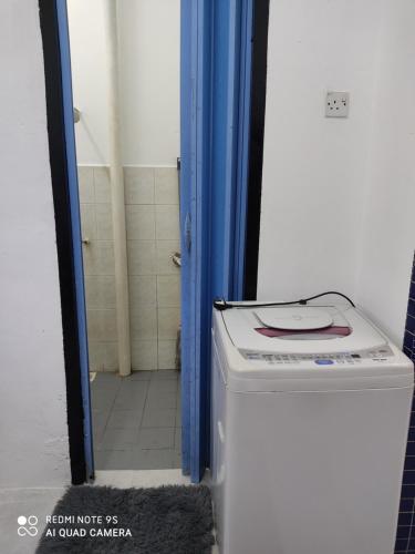 a bathroom with a washing machine and a blue door at R&R HOMESTAY TAMAN HARMONI in Simpang Renggam