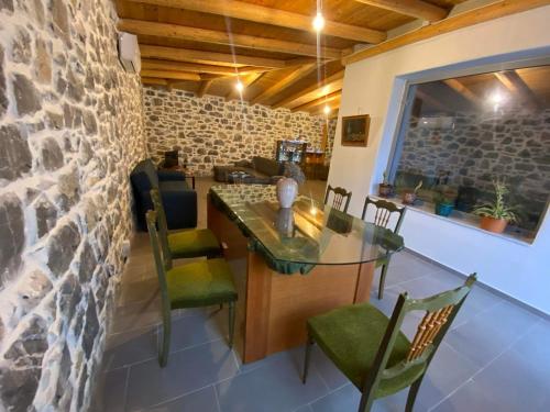a dining room with a stone wall and a table and chairs at Rouvas Villas in Apomarmá
