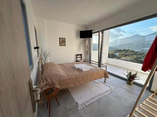a bedroom with a bed and a large window at Rouvas Villas in Apomarmá