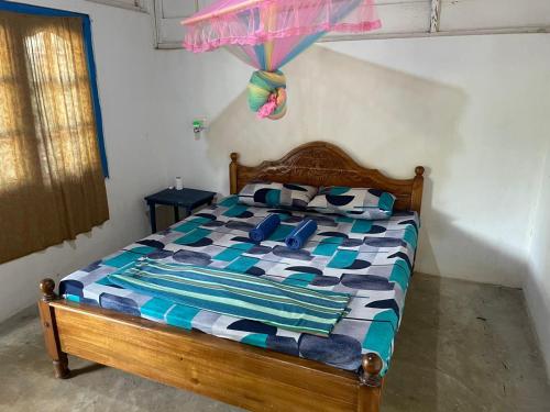 a bedroom with a wooden bed with a colorful comforter at araliya villa in Kalpitiya