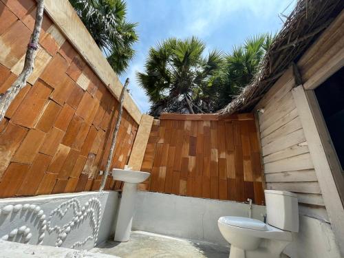 a bathroom with a toilet and a wooden fence at araliya villa in Kalpitiya