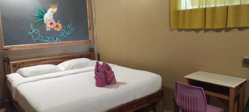 a bedroom with a bed and two purple chairs at Lazy Hut in Ko Phayam