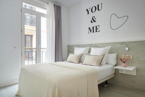 a white bedroom with a bed and a sign that says you and me at Pension El Puerto in San Sebastián