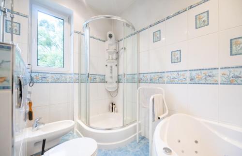 a bathroom with a tub shower and a sink at Willa Zacisze - Pokoje Gościnne in Wrocław