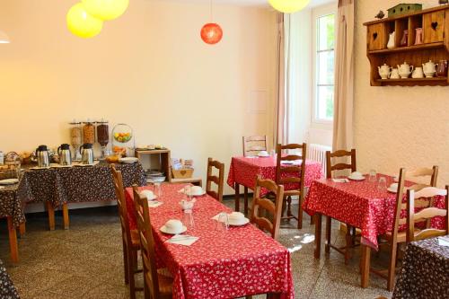 a dining room with tables and chairs with red tablecloths at Hôtel du Château in Annecy