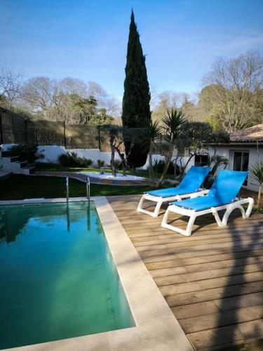 - deux chaises bleues installées à côté de la piscine dans l'établissement Au Petit Mazet - 4 personnes, à Nîmes