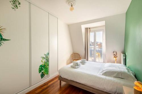 a bedroom with a bed with two cups and a window at Secrétan - Charmant appartement au pied des Buttes Chaumont in Paris