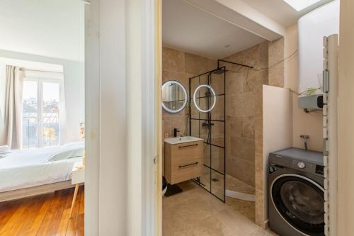 a bathroom with a washing machine and a washer and dryer at Secrétan - Charmant appartement au pied des Buttes Chaumont in Paris