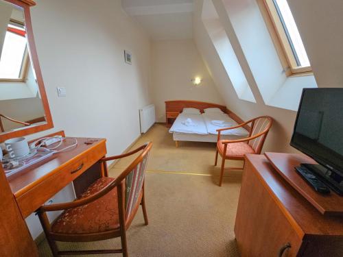 a attic room with a bed and a desk and chairs at Willa Sanssouci in Kudowa-Zdrój