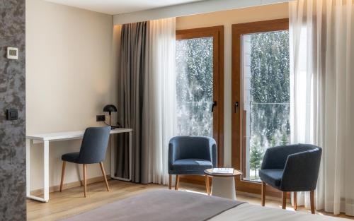 a bedroom with two chairs and a desk in front of a window at Hotel Montarto in Baqueira-Beret