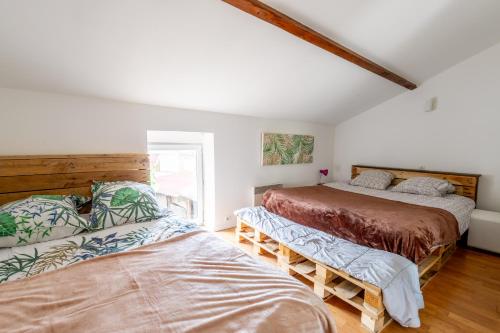 two beds in a room with white walls and wood floors at Maison familiale sud Nantes in Bouguenais