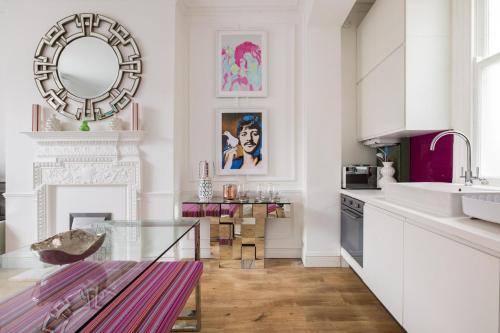 a kitchen with a glass table and a mirror at Cosy and Stylish Chelsea 2 bedroom flat in London